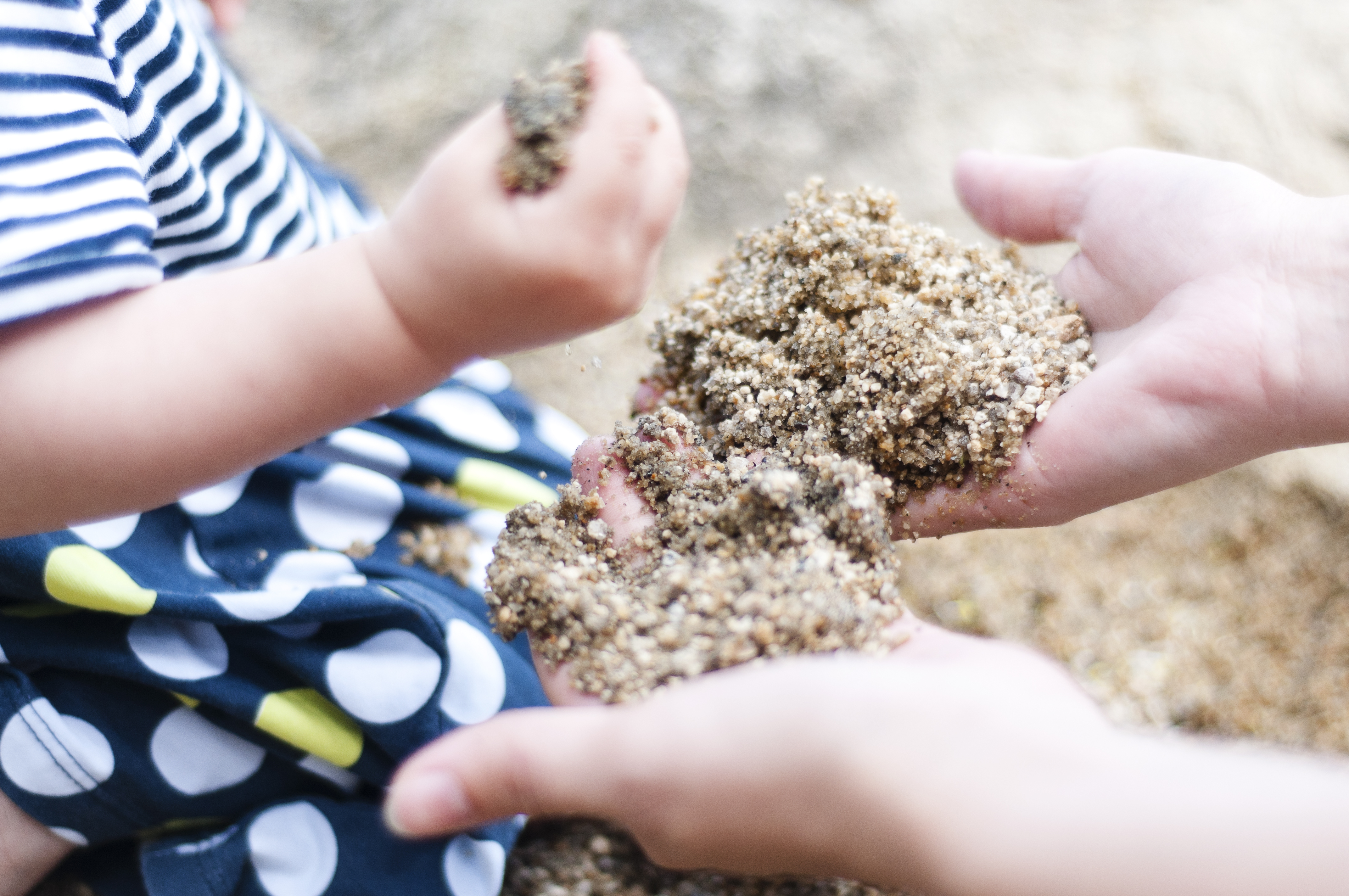 adult and tiny hands explore sand